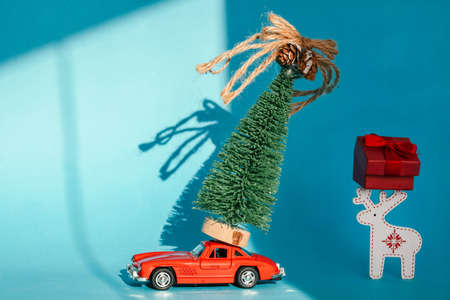 Red toy car with a christmas tree on the roof, white background. Copy space. Concept new year.の写真素材