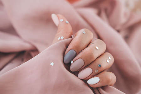 Women - hand with beautiful manicure hold a silk fabric. Autumn trend, polish the beige and quail pattern on the nails with gel polish, shellac. Copy space.の写真素材
