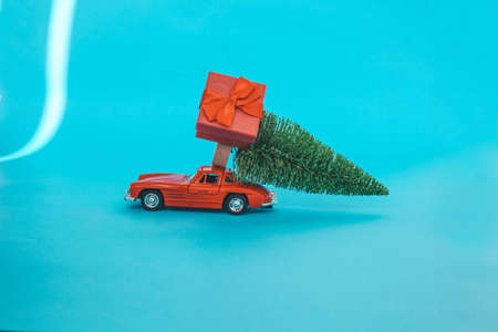 Red toy car with a christmas tree on the roof, white background. Copy space. Concept new year.の写真素材