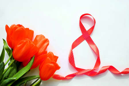 Red tulips and ribbon with number 8 on a white background. International Women's Day 8 March. copyspace.の写真素材