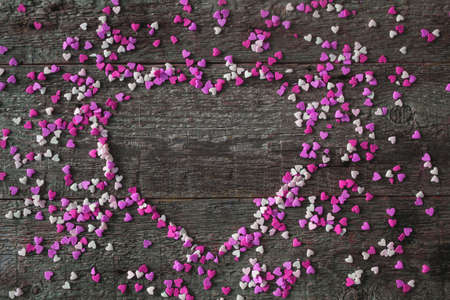 Sweet hearts violet color in the shape of a heart on a wooden background. Frame in the heart of valentines day concept. copyspace.の写真素材