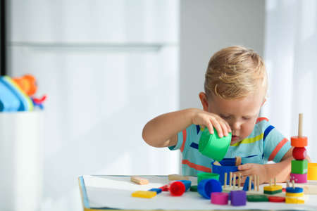 A little boy plays with wooden toys and builds a tower. Educational logic toys for children. Montessori games for child development. Children's wooden toy.の写真素材