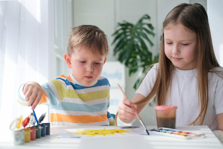 Brother and sister draw a picture with paints on a piece of paper. Children are learning to draw. home creativity.の写真素材