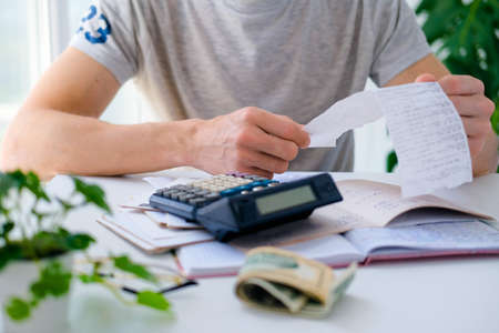 A man counts a bill on a calculator on the table. Payment of utility services. Saving energy and money concept.の写真素材