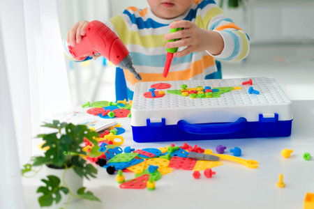 Little boy playing set with a screwdriver and a drill, and screws and parts . The child plays...