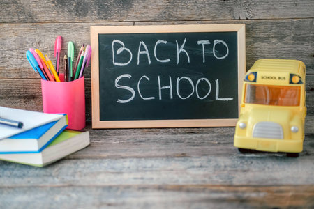 School board with the inscription back to school on a wooden background. School concept, books, pens, pencils and school bus. copyspace.の写真素材