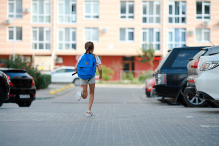 A schoolgirl girl runs with a briefcase on her back to school. back to school.の写真素材
