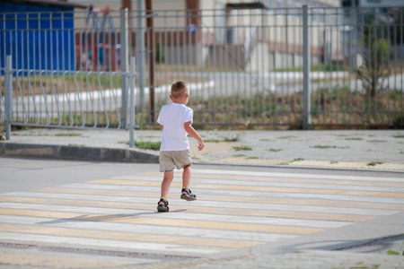 A little boy is running along the crosswalk. The child runs along the road to kindergarten and school. Zebra walking in the city. Concept of pedestrians passing crosswalkの写真素材