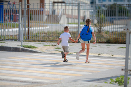 Brother and sister run across a pedestrian crossing. Children Run along the road to kindergarten and school.Zebra traffic walk way in the city. Concept pedestrians passing a crosswalkの写真素材