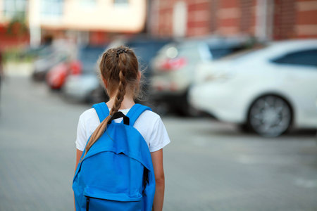A schoolgirl girl with a briefcase on her back goes to school. back to school.の写真素材
