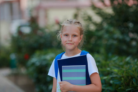 Portrait of a girl with a briefcase and notebooks in her hands on the street. back to school.の写真素材