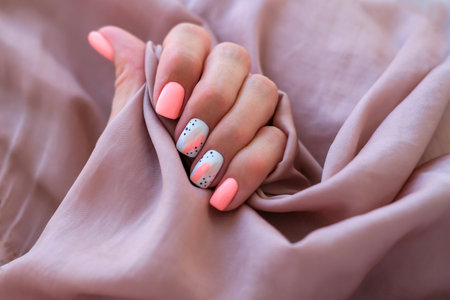 Women - a hand with a beautiful manicure holds a silk fabric. Spring trend, pink nails, drawing on nails with gel polish, shellac. copyspace.の写真素材