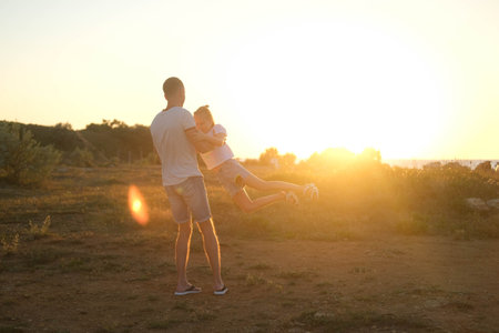 Dad is circling daughter against the backdrop of sunset. happy father and childの写真素材