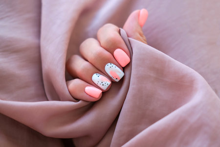 Women - a hand with a beautiful manicure holds a silk fabric. Spring trend, pink nails, drawing on nails with gel polish, shellac. copyspace.の写真素材