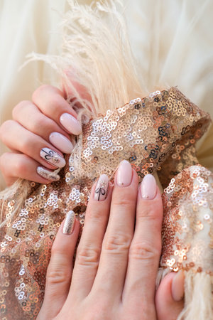 Beautiful female hand with a Christmas nail design on a golden background. Nail design, manicure with a pattern of Christmas balls. sequins. Shellac, gel polish.の写真素材
