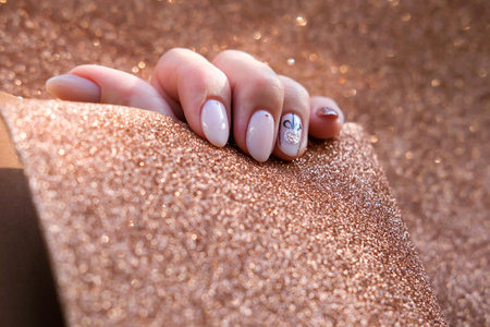 Beautiful female hand with a Christmas nail design on a golden background. Nail design, manicure with a pattern of Christmas balls. sequins. Shellac, gel polish.の写真素材