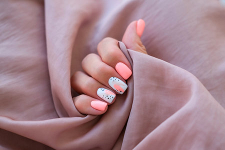 Women - a hand with a beautiful manicure holds a silk fabric. Spring trend, pink nails, drawing on nails with gel polish, shellac. copyspace.の写真素材