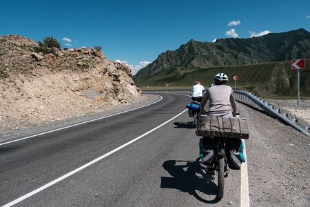 Cyclists ride on a road in the Altai mountainsの写真素材