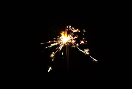 Shiny firework particles spark flare pyrotechnics at nightの写真素材