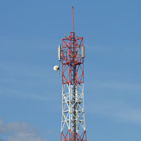 Red and white roof top cellular tower under blue sky