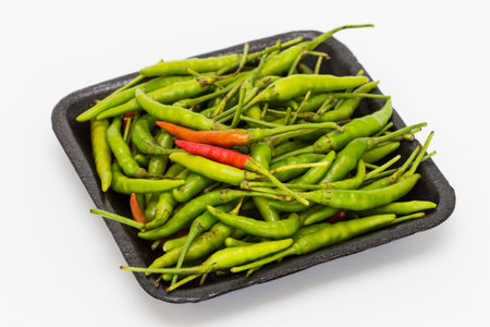 Green pepper in black tray on a white background.