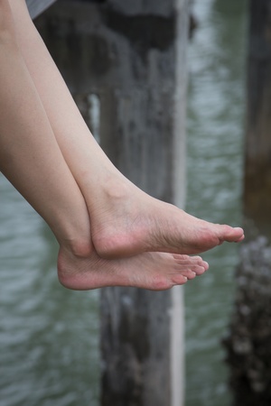 Woman sitting on a wood fence near the beachの写真素材