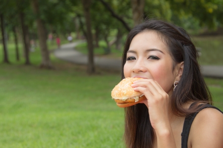 Teenage Girl Eating a Cheeseburger in the parkの写真素材