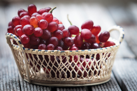 Bunch of ripe white grapes in a wicker basket on a white backgroundの写真素材