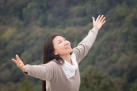Asian woman outstretched hands touch the good nature in forest on the top hillのeditorial素材