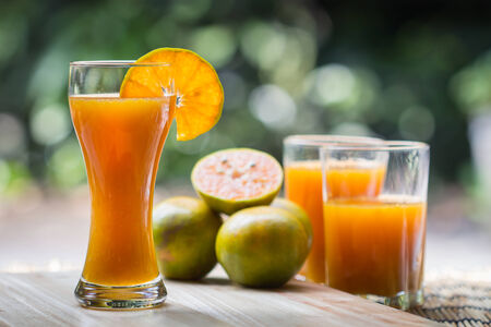 Glass of fresh orange juice with sliced orange half on wooden tableの写真素材