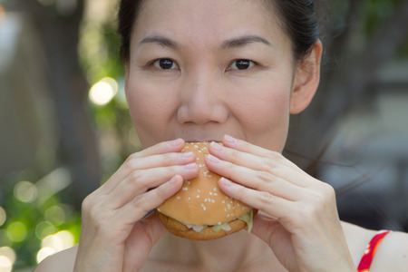 Asian girl eating a hamburger in a swimsuit.の写真素材