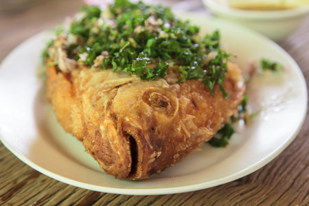 Fried fish with herbs and served on a white plateの写真素材