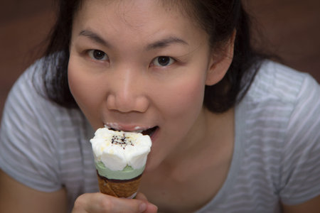 Asian girl eating ice cream happily.の写真素材