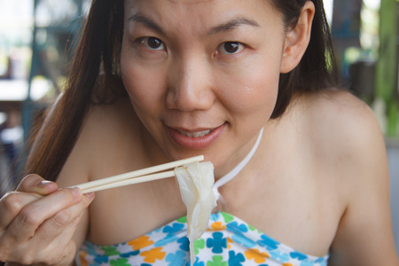 Beautiful Asian woman eating noodles with spicy.の写真素材
