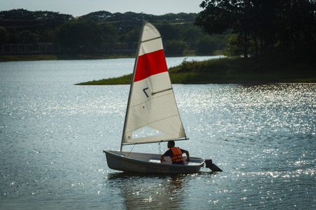 Man sailing a white sailboat in nature lake