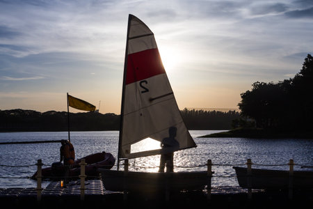 man with sailing boat in marina at sunsetの写真素材