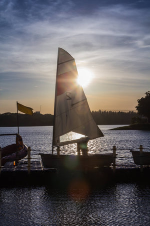 man with sailing boat in marina at sunsetの写真素材