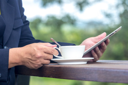 businessman working on tablet and holding coffee cupの写真素材