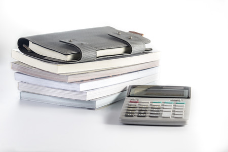 note book paper with pile of books and calculators on white backgroundの写真素材