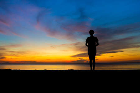 women playing yoga at beachside on sunsetの写真素材