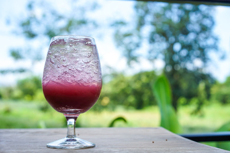 grape soda on wooden table in the gardenの写真素材
