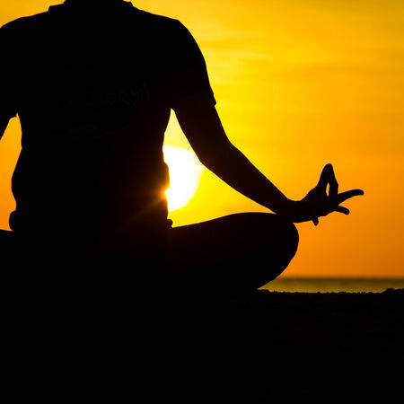 women playing yoga at beachside on sunsetの写真素材