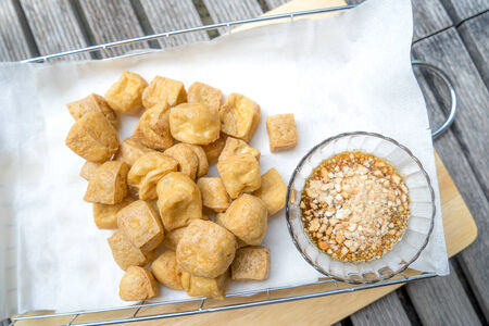Fried tofu with spicy peanut sauce on cutting boardの写真素材
