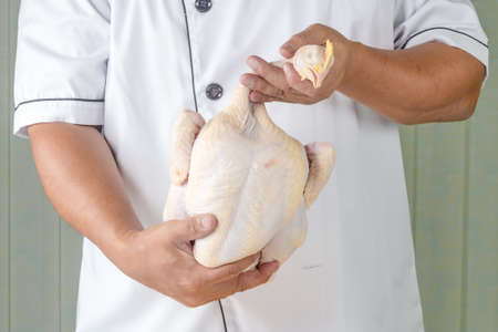 chef holding raw chicken in kitchen roomの写真素材