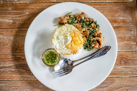 thai Fried Chicken with Basil and fried egg on wooden tebleの写真素材