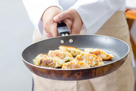 chef making Gyoza (Japanese Dumplings)  in frying panの写真素材