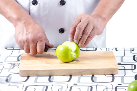chef cutting green apple on chopping boardの写真素材