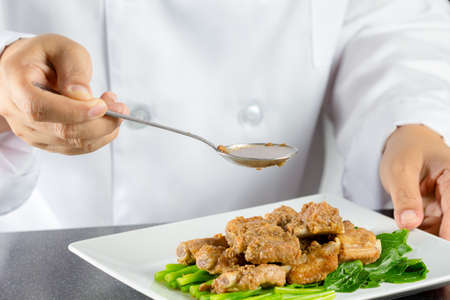 Chef making stir fried chinese kale and pork ribs in the kitchenの写真素材