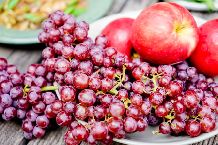 Red grape fruits with apple in the dish on woodenの写真素材