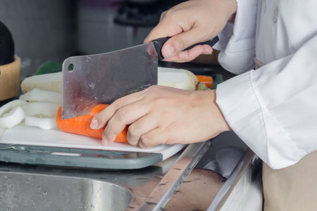 woman hand cutting carrots in kitchenの写真素材